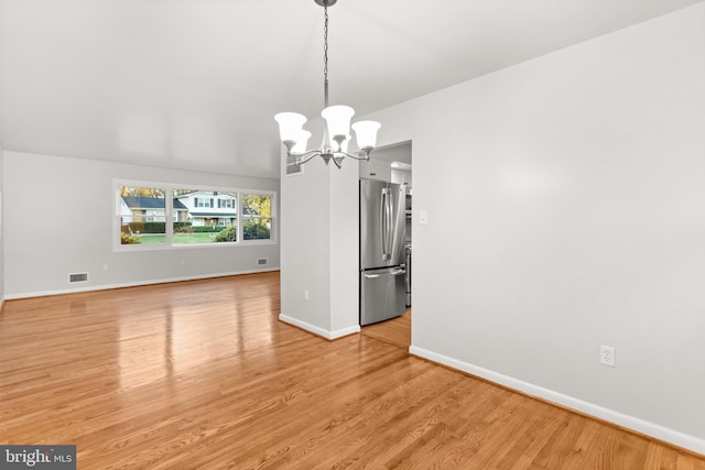 unfurnished dining area with light wood-type flooring, visible vents, a notable chandelier, and baseboards