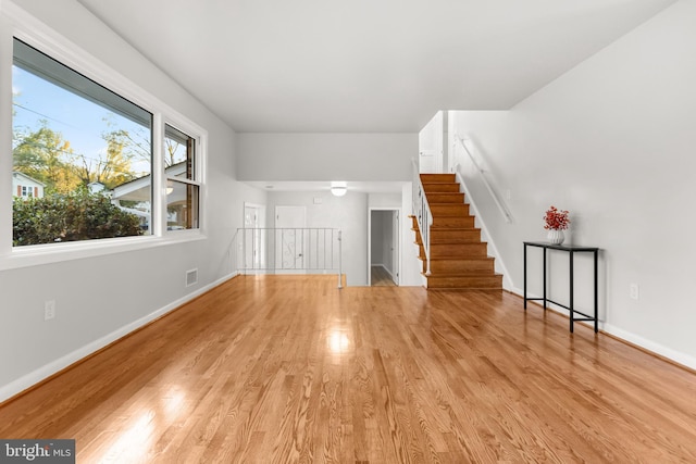 unfurnished living room with baseboards, visible vents, and wood finished floors