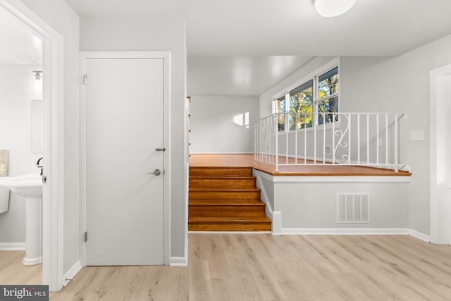 foyer entrance featuring stairway, wood finished floors, visible vents, and baseboards