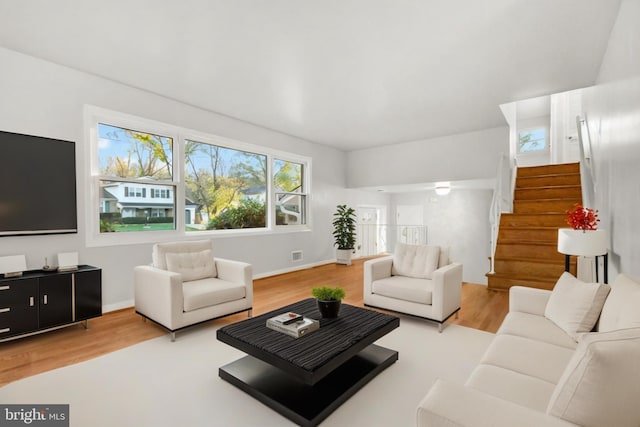 living area with visible vents, stairs, baseboards, and wood finished floors