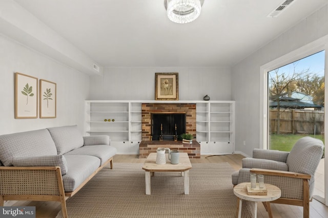 living room with a fireplace, wood finished floors, and visible vents