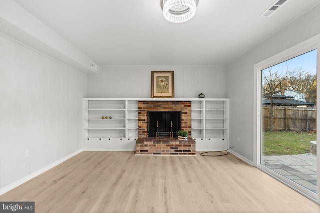 unfurnished living room featuring a fireplace, wood finished floors, visible vents, and baseboards