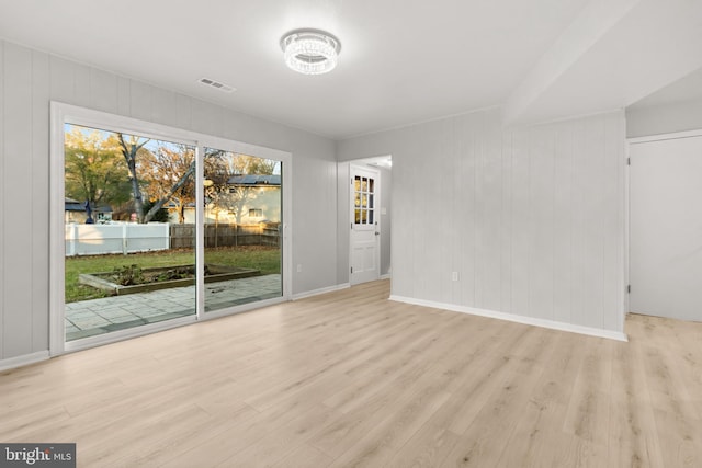 empty room with wood finished floors, visible vents, and baseboards