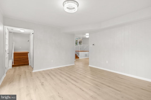 unfurnished living room featuring light wood finished floors, stairs, and baseboards