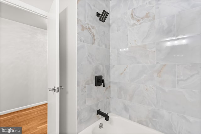 bathroom with bathtub / shower combination, baseboards, and wood finished floors