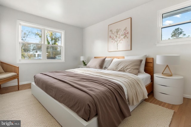 bedroom featuring light wood finished floors and baseboards