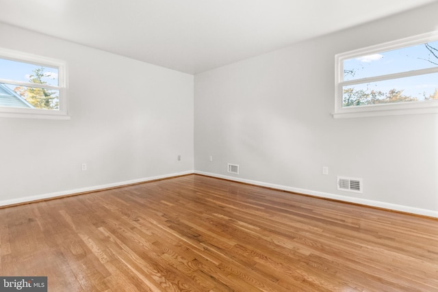 unfurnished room featuring visible vents, baseboards, and wood finished floors