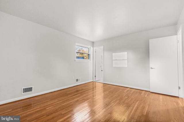 spare room with visible vents, baseboards, and wood finished floors