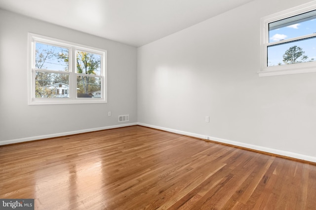 empty room with baseboards, visible vents, and wood finished floors