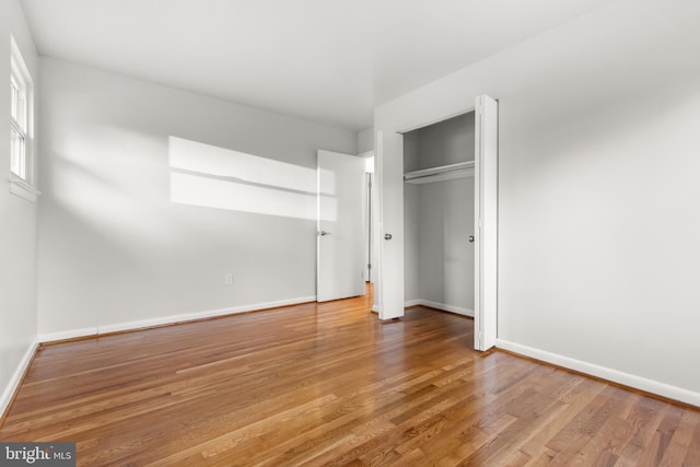 unfurnished bedroom featuring a closet, baseboards, and wood finished floors