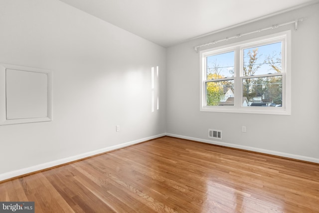 unfurnished room featuring visible vents, baseboards, and wood finished floors