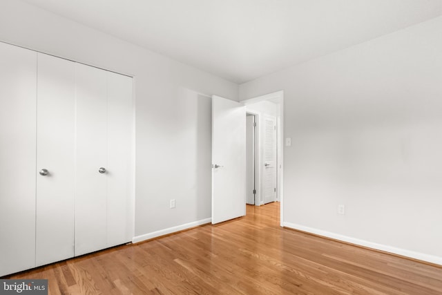 unfurnished bedroom featuring a closet, wood finished floors, and baseboards