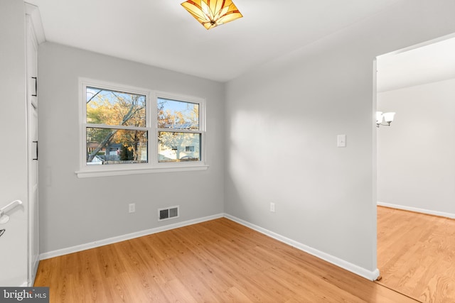 spare room featuring light wood finished floors, baseboards, and visible vents