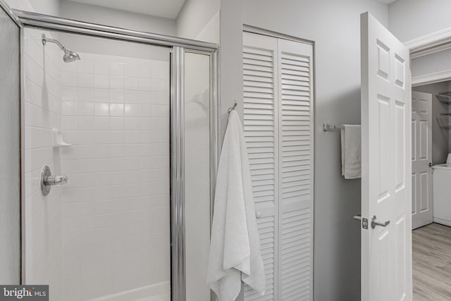 bathroom featuring a closet, a shower stall, and wood finished floors