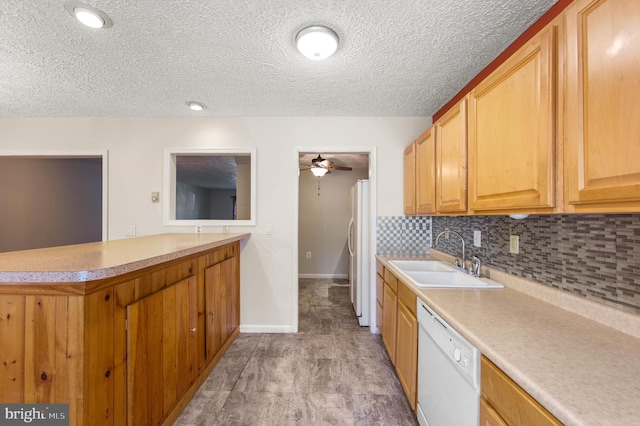 kitchen featuring white appliances, tasteful backsplash, ceiling fan, a peninsula, and a sink