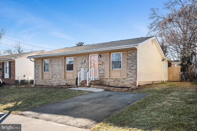 ranch-style home featuring a shingled roof, a front yard, brick siding, and fence