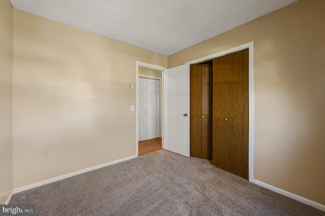 unfurnished bedroom with a textured ceiling, a closet, carpet flooring, and baseboards