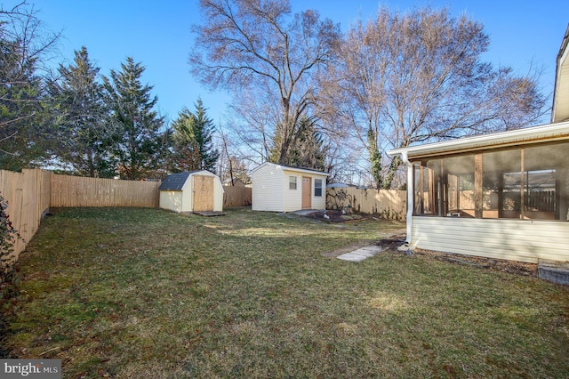 view of yard featuring a sunroom, a fenced backyard, a shed, and an outdoor structure