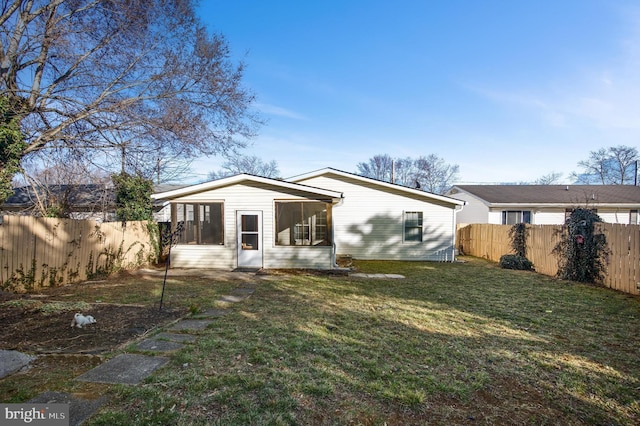 back of property with a lawn, a fenced backyard, and a sunroom