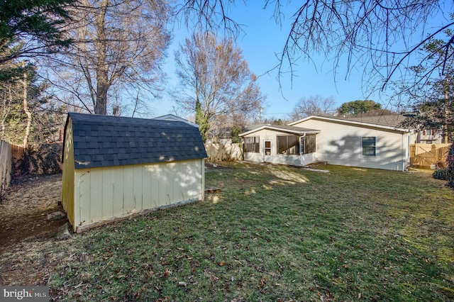 view of yard with a sunroom, a shed, a fenced backyard, and an outbuilding