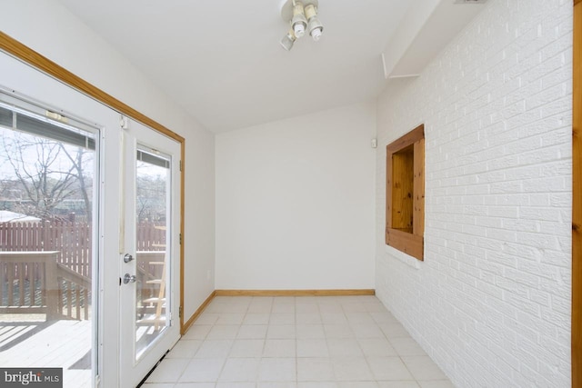 spare room with brick wall and baseboards