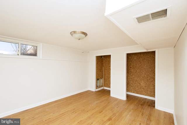 interior space with visible vents, two closets, baseboards, and wood finished floors