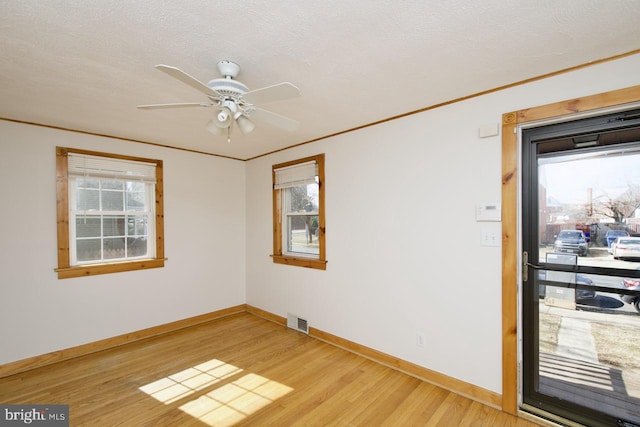 unfurnished room featuring visible vents, crown molding, light wood-style flooring, and baseboards