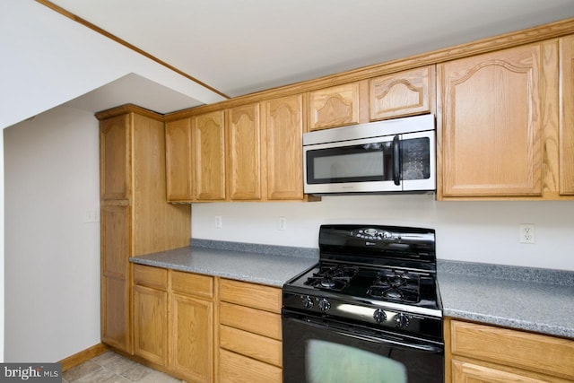 kitchen with black range with gas cooktop, stainless steel microwave, and light brown cabinetry