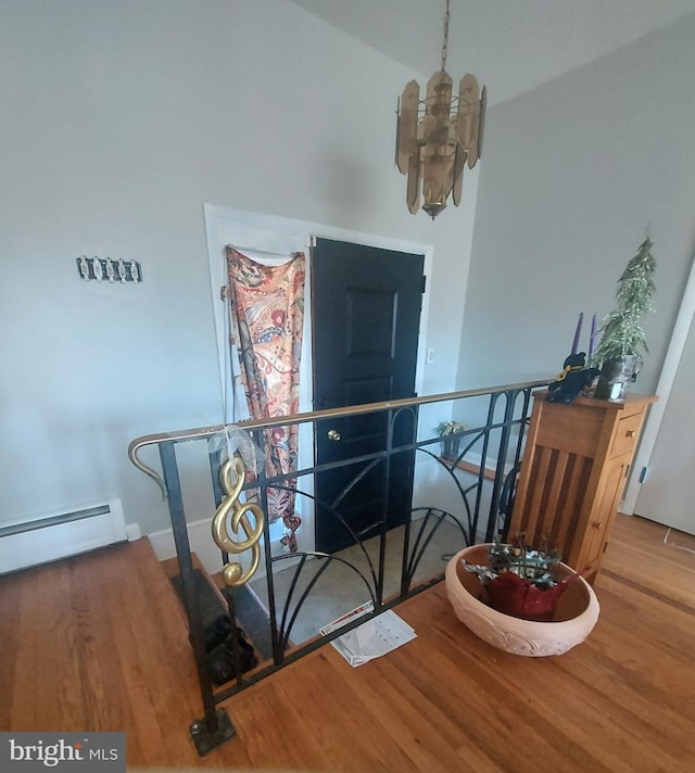 interior space featuring a notable chandelier, baseboard heating, and wood finished floors