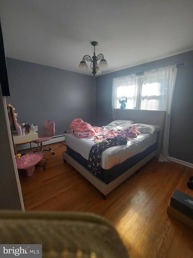 bedroom with a notable chandelier, wood finished floors, baseboards, and a baseboard radiator