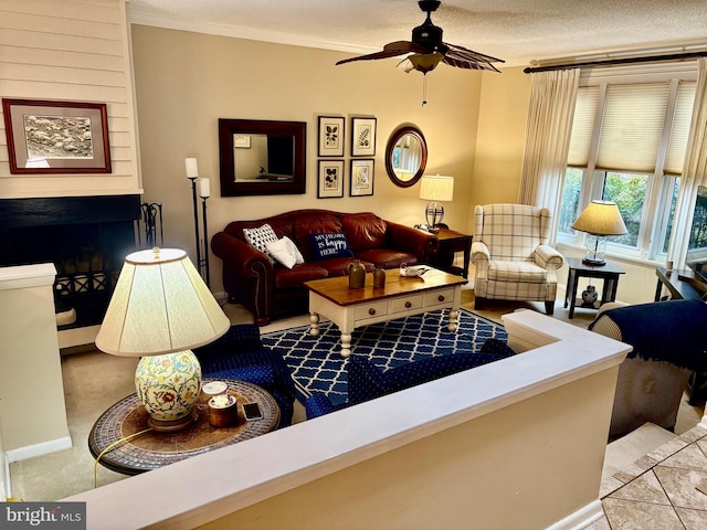 living area featuring a textured ceiling, a fireplace, a ceiling fan, and crown molding