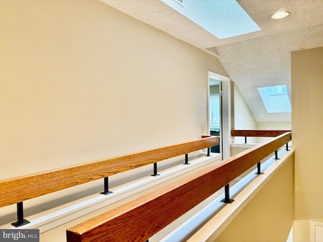 hallway featuring a textured ceiling and vaulted ceiling with skylight