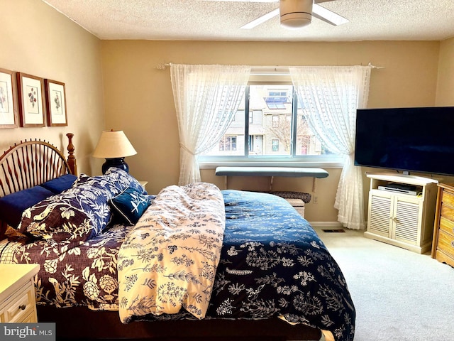 carpeted bedroom with a textured ceiling, ceiling fan, visible vents, and baseboards