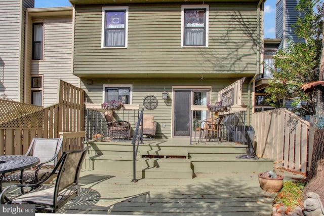 back of house featuring fence, a wooden deck, and stairs