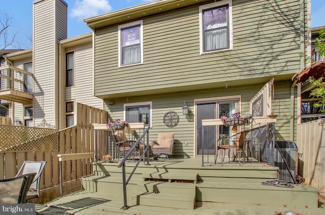 rear view of property with fence, a chimney, and a wooden deck