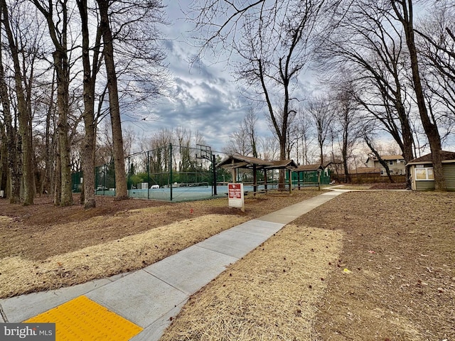 surrounding community featuring a tennis court and fence