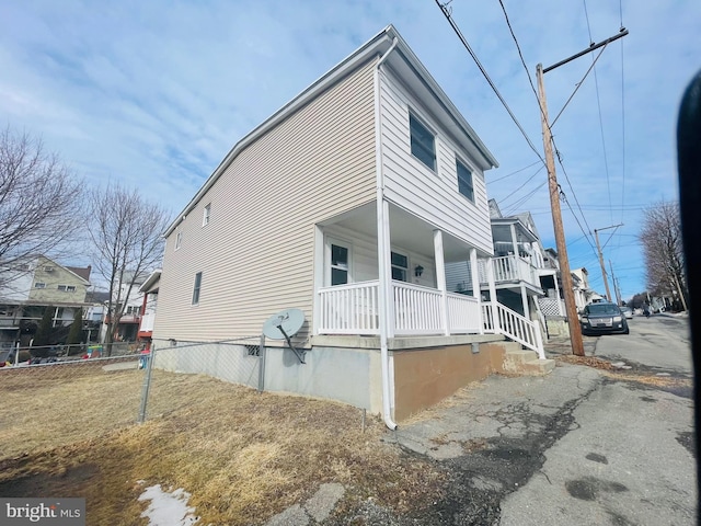 view of home's exterior with a porch and fence