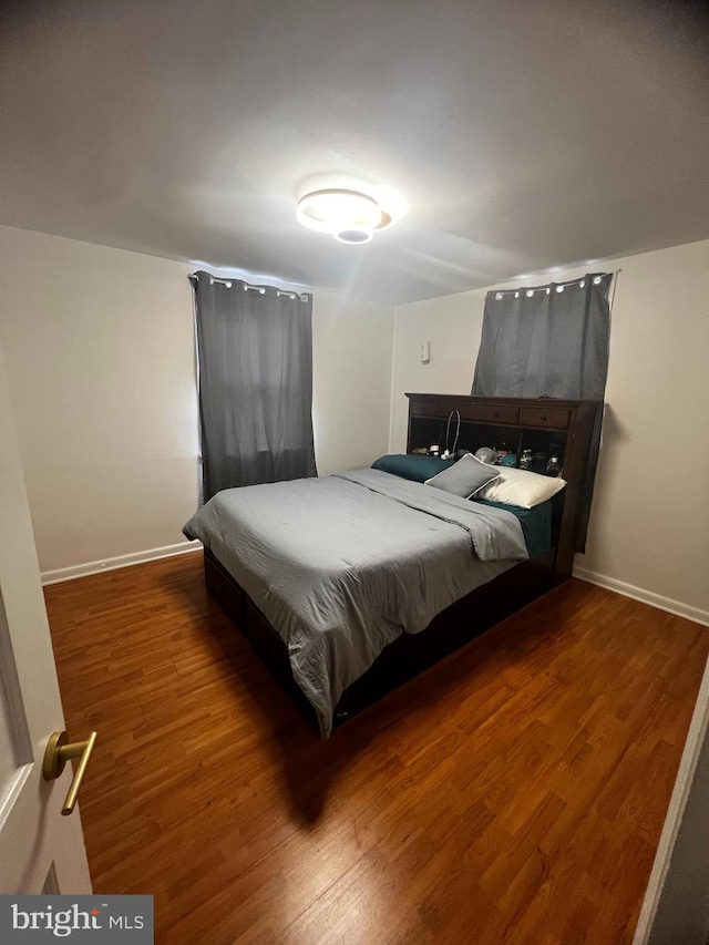 bedroom with baseboards and wood finished floors