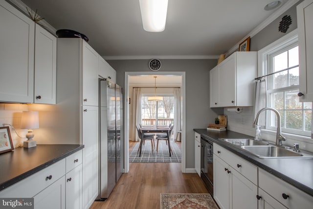 kitchen featuring a sink, ornamental molding, freestanding refrigerator, decorative backsplash, and dark countertops