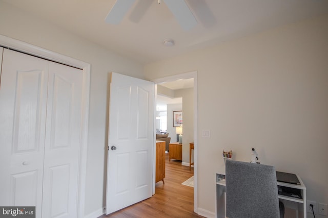 office space with light wood finished floors, a ceiling fan, and baseboards