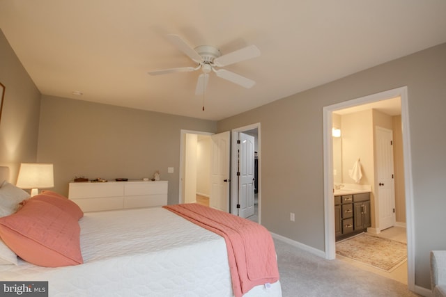 bedroom featuring baseboards, ceiling fan, ensuite bath, and light colored carpet