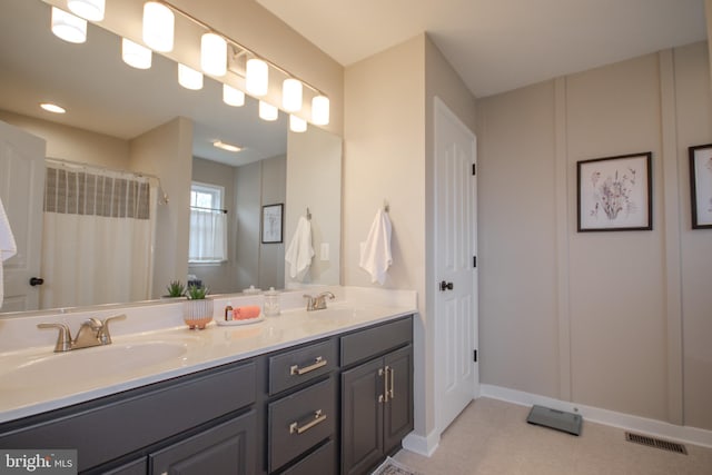 full bath with double vanity, baseboards, visible vents, and a sink