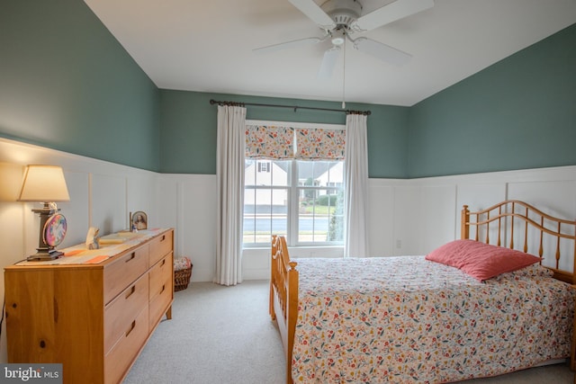 bedroom featuring light carpet, a wainscoted wall, and a ceiling fan