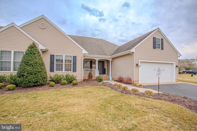 view of front facade with an attached garage, aphalt driveway, a porch, and a front yard