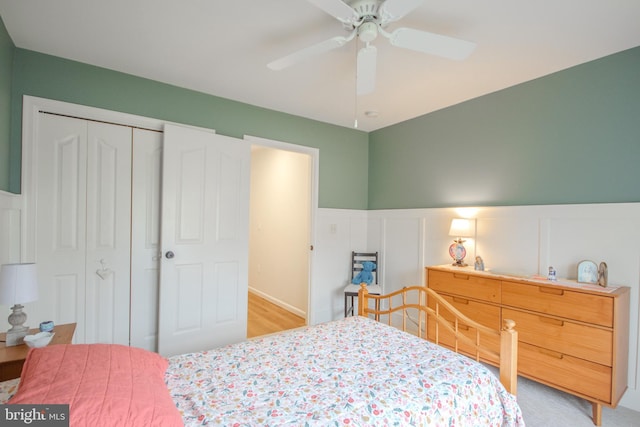 bedroom with a closet, wainscoting, and a ceiling fan