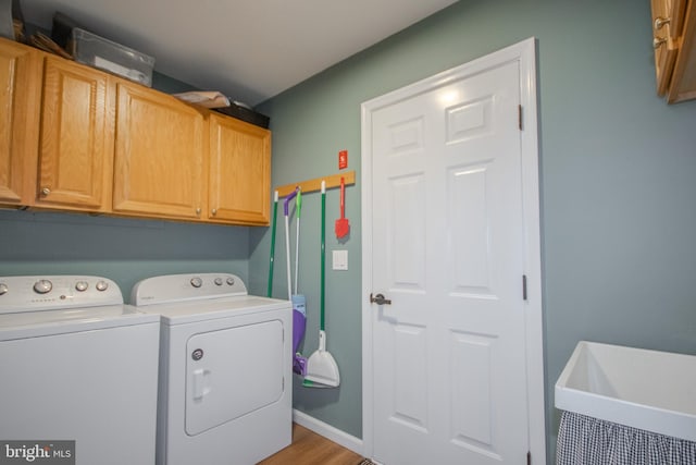 laundry room with cabinet space, baseboards, separate washer and dryer, and a sink