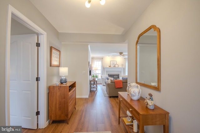 corridor featuring light wood-type flooring and baseboards