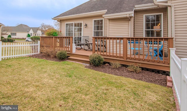 rear view of property featuring roof with shingles, a lawn, fence, and a wooden deck