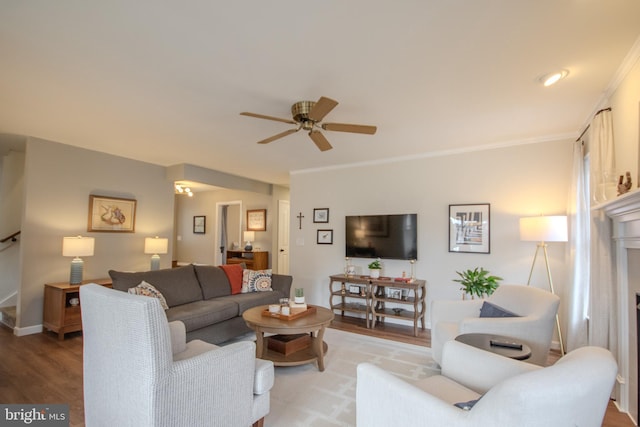 living room featuring crown molding, stairway, ceiling fan, wood finished floors, and baseboards