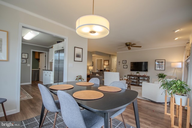 dining area featuring a ceiling fan, crown molding, baseboards, and wood finished floors